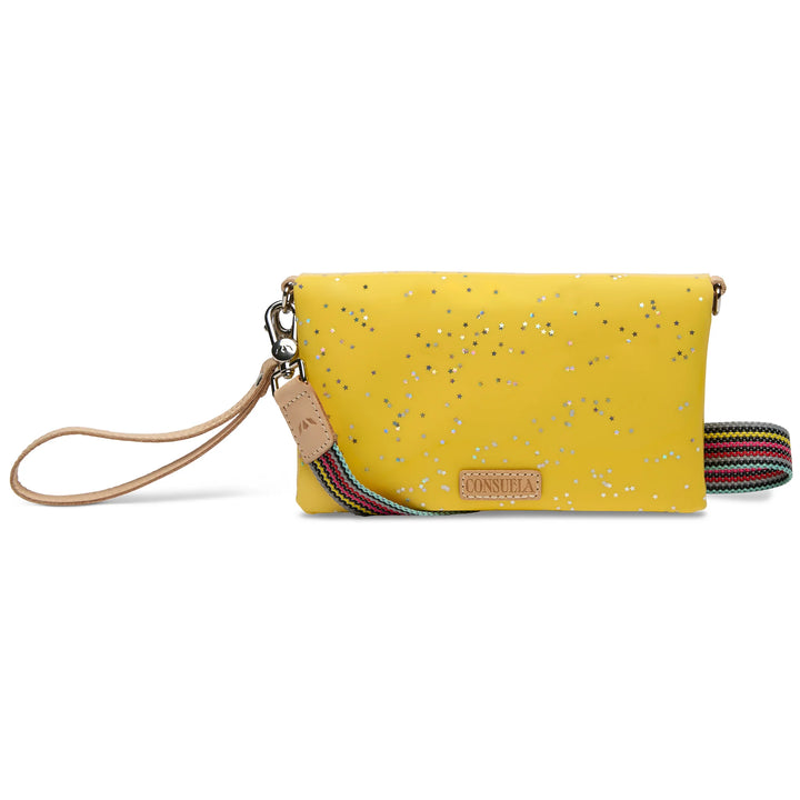Consuela Harlow Uptown Crossbody in yellow glitter with iridescent star patterns and natural leather trim.