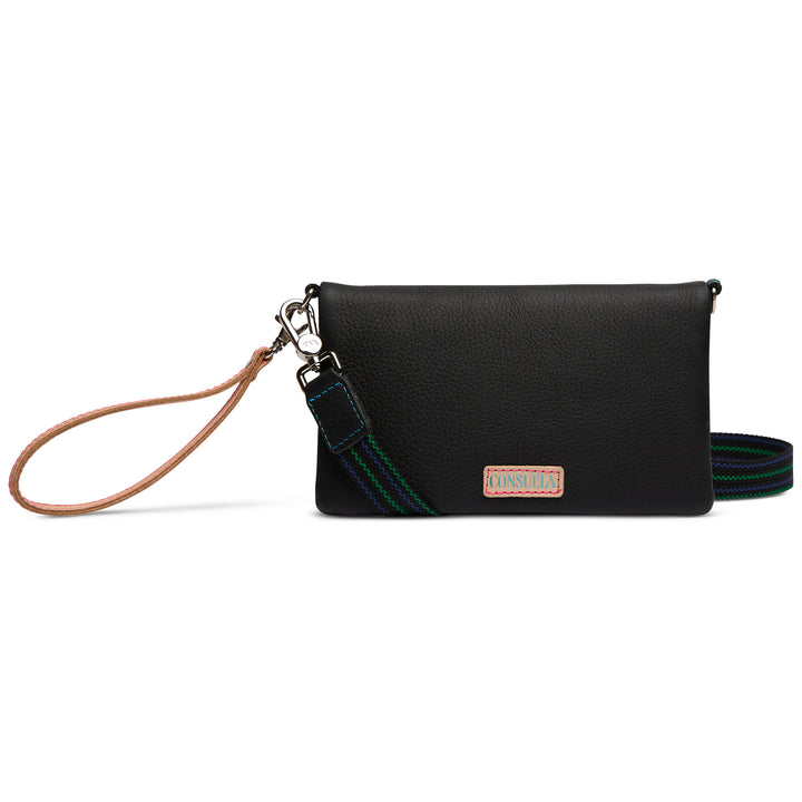Consuela Cyndi Uptown Crossbody in black pebbled leather with fold-over flap and blue-and-green woven crossbody strap