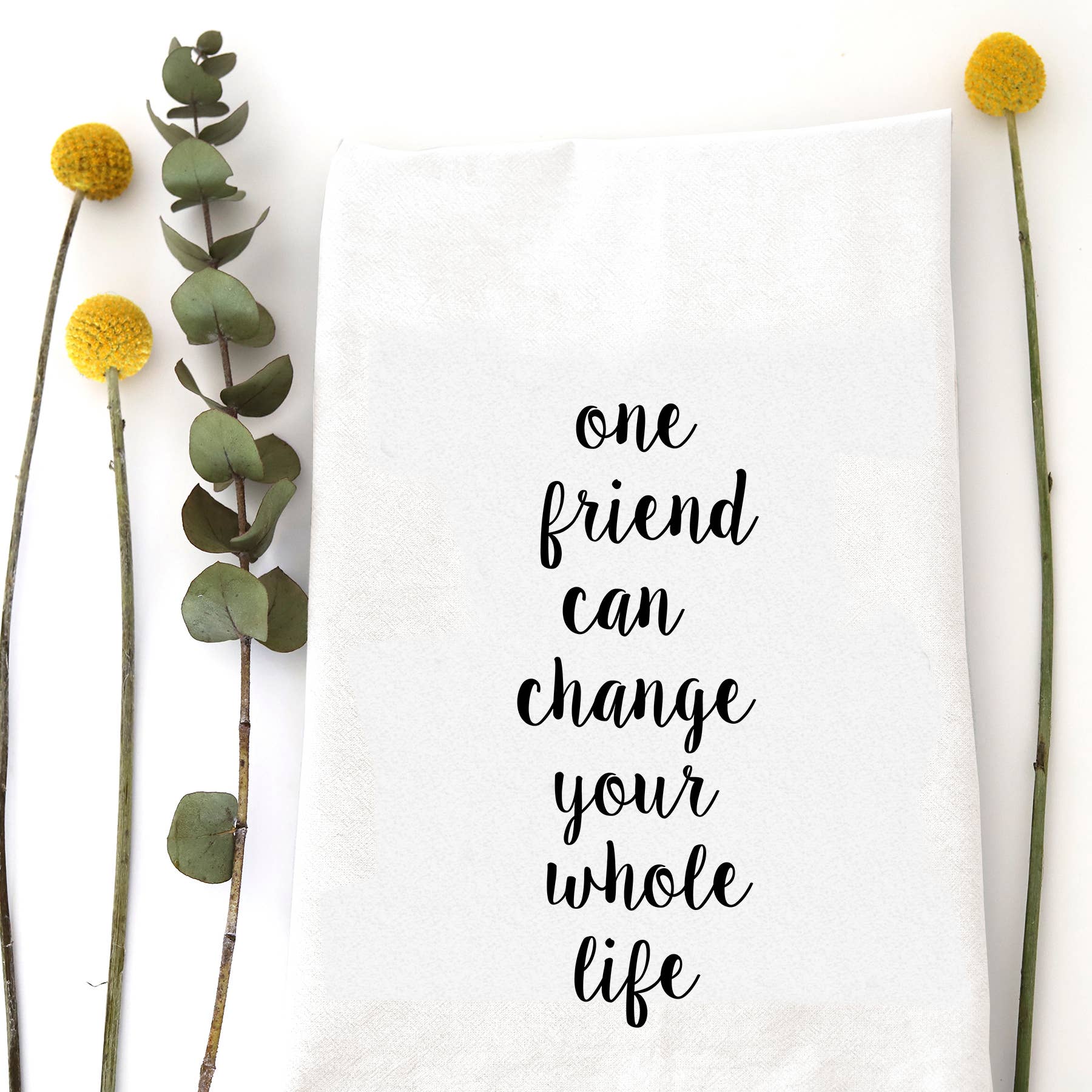 White cotton flour sack tea towel featuring the sentimental quote "One friend can change your whole life" in elegant black script.