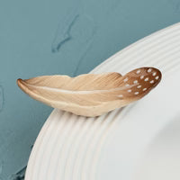 Nora Fleming Creative Quill Mini (A450) – A hand-painted ceramic brown and tan feather mini with white polka dot details, designed to fit Nora Fleming bases.