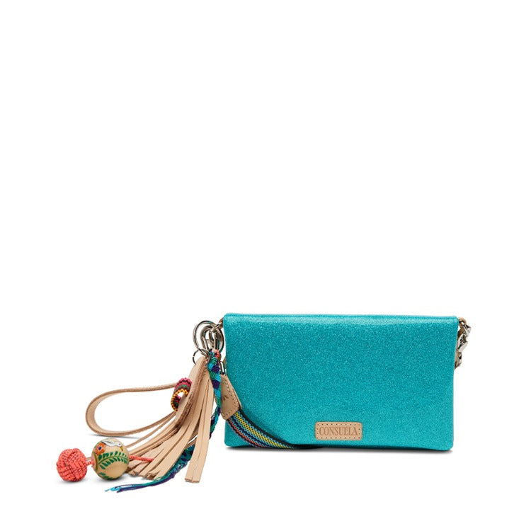 Consuela Lumi Uptown Crossbody featuring iridescent turquoise fabric with a colorful woven strap and beaded tassel detail.