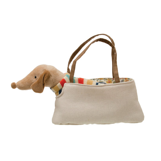 Brown cotton plush dachshund wearing a sweater sitting inside a fabric dog carrier bag.