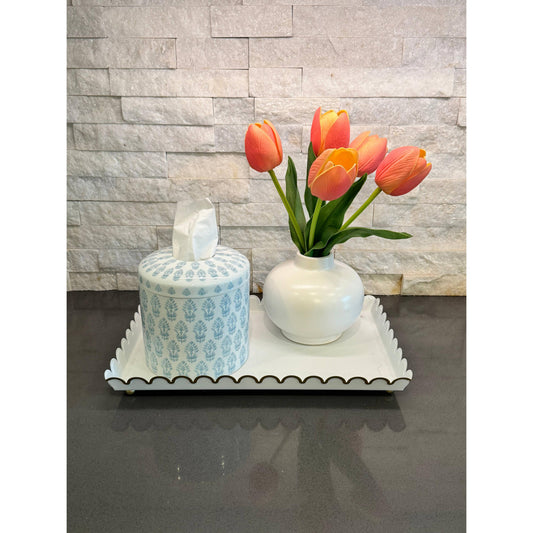 The Eleanor blue and white block-print ceramic tissue box cover styled on a decorative tray with a vase of orange tulips and a candle.