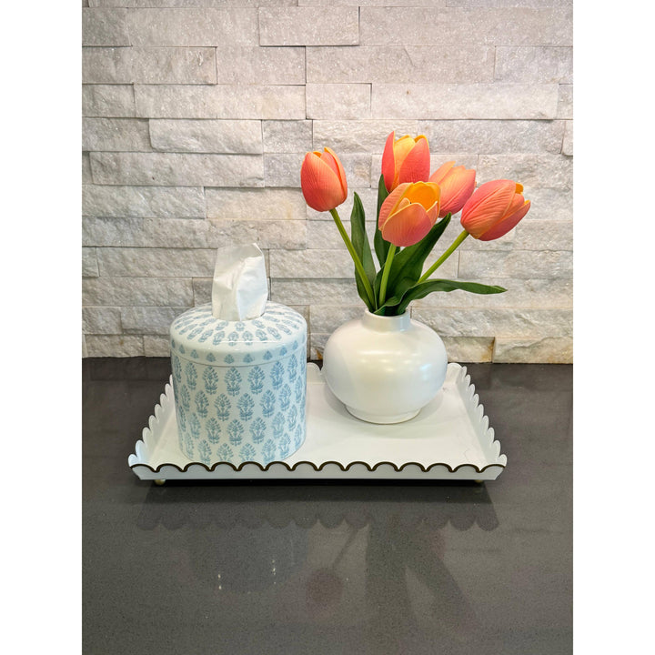 The Eleanor blue and white block-print ceramic tissue box cover styled on a decorative tray with a vase of orange tulips and a candle.