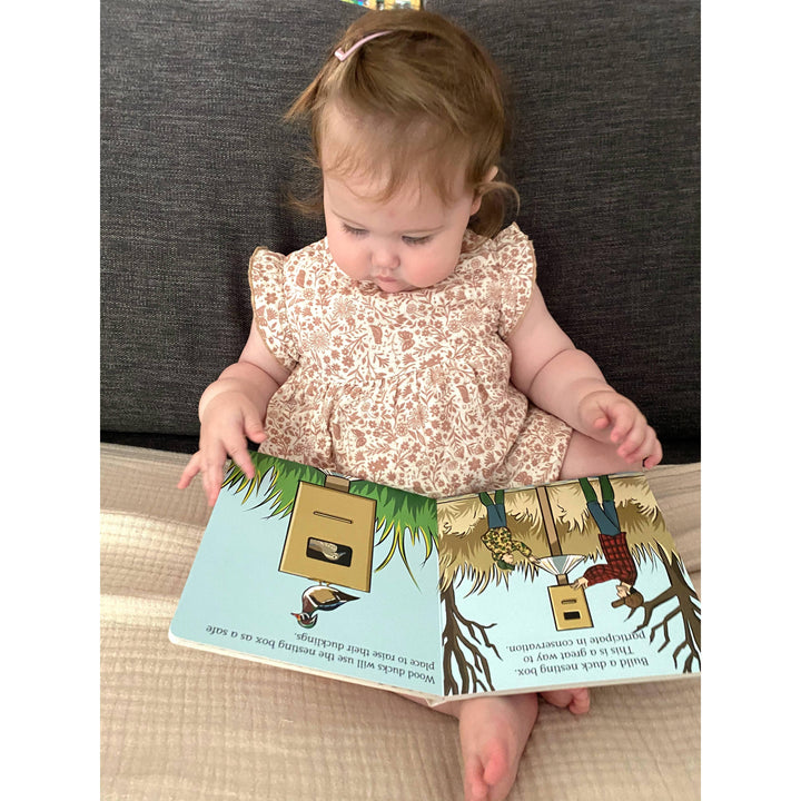 Toddler reading the Duck Hunt board book in a cozy nursery setting