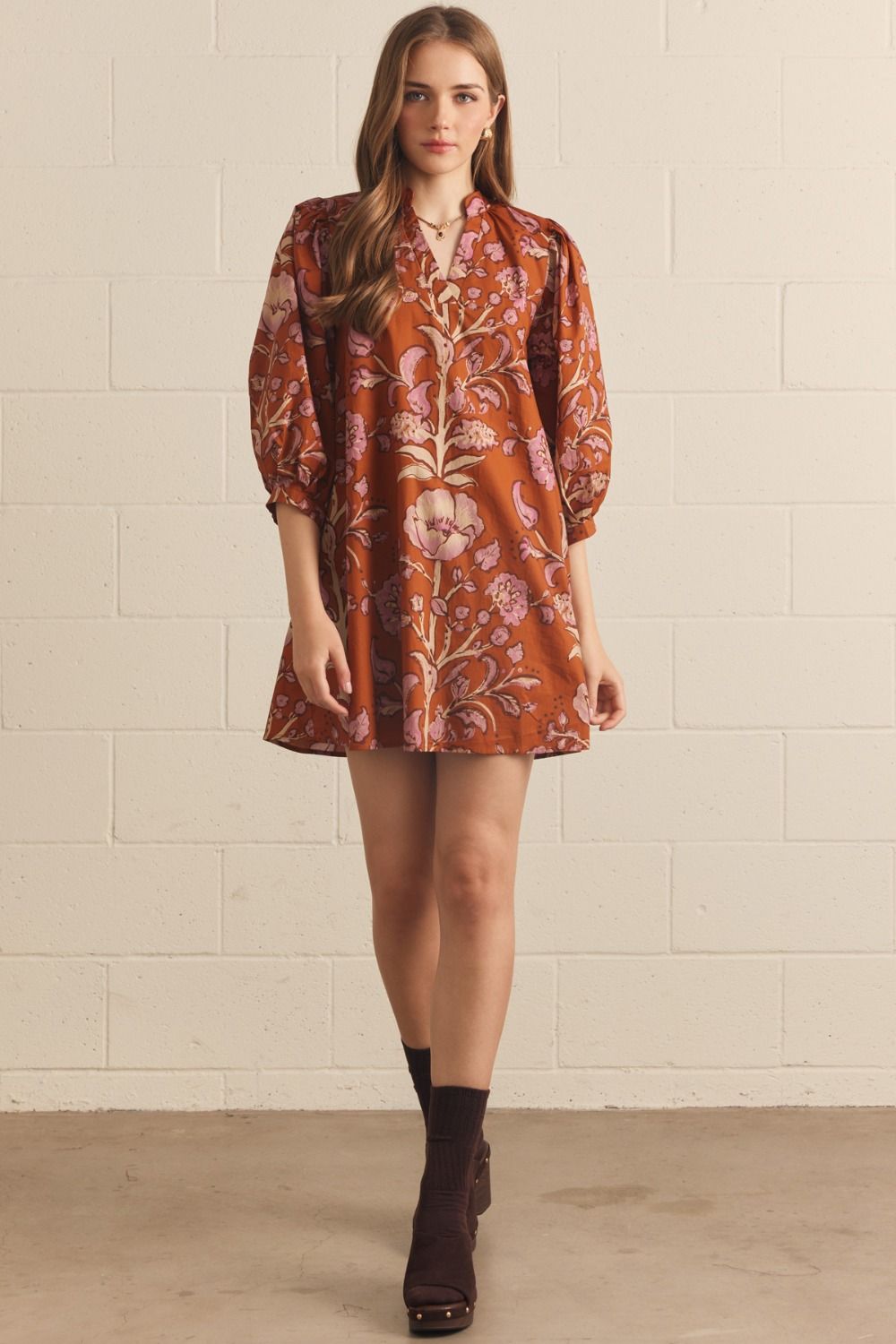 Model wearing the Entro Autumn Floral Mini Dress in Rust, featuring 3/4 puff sleeves, a V-neck, and side pockets.