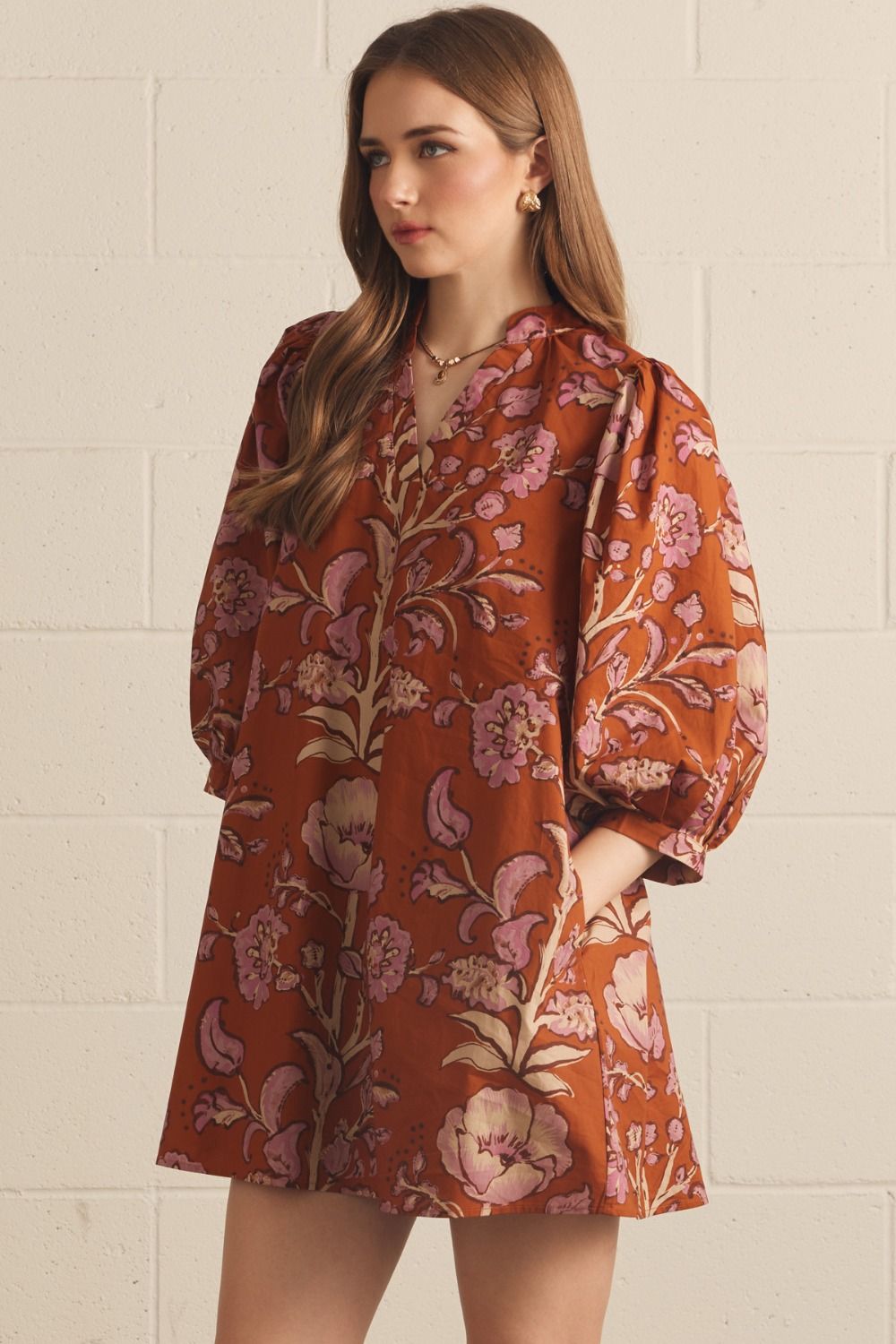 Model wearing the Entro Autumn Floral Mini Dress in Rust, featuring 3/4 puff sleeves, a V-neck, and side pockets.