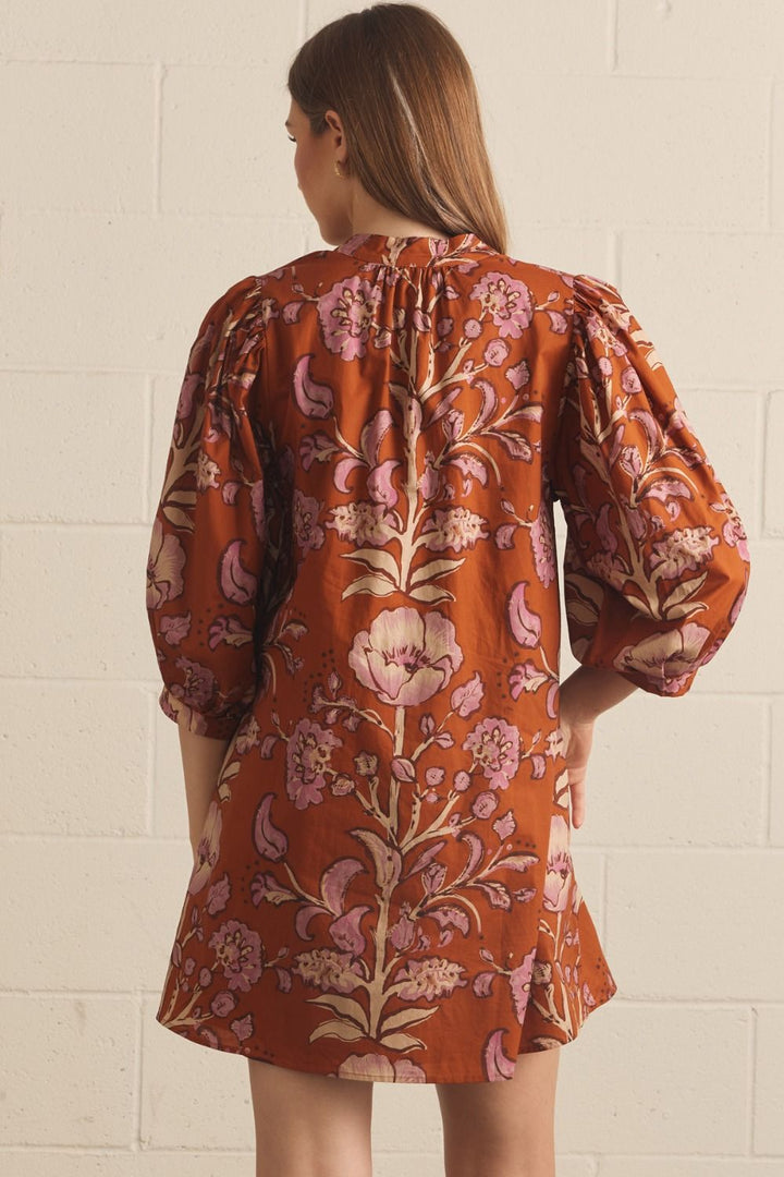 Model wearing the Entro Autumn Floral Mini Dress in Rust, featuring 3/4 puff sleeves, a V-neck, and side pockets.