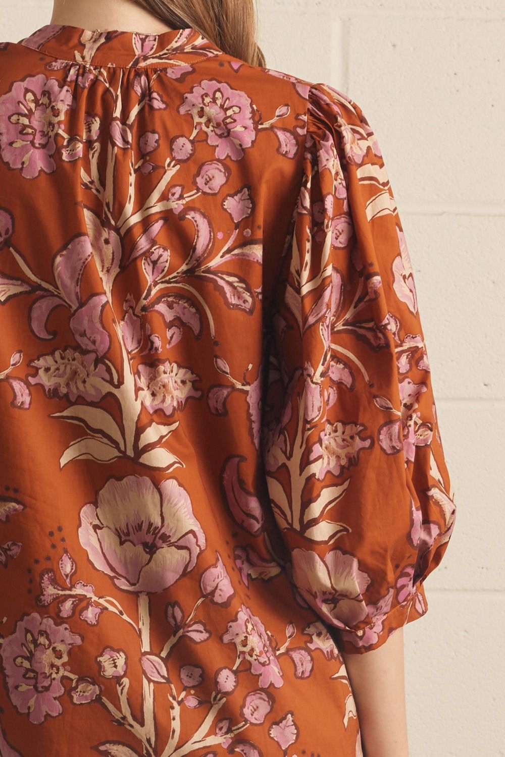 Model wearing the Entro Autumn Floral Mini Dress in Rust, featuring 3/4 puff sleeves, a V-neck, and side pockets.