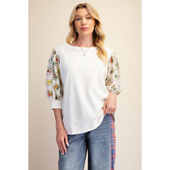 Close-up of floral embroidery on Easel ivory puff sleeve top