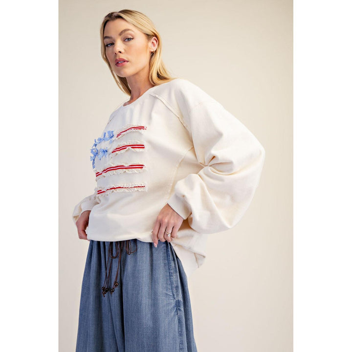Ivory oversized terry knit pullover with patchwork flag and gingham bows