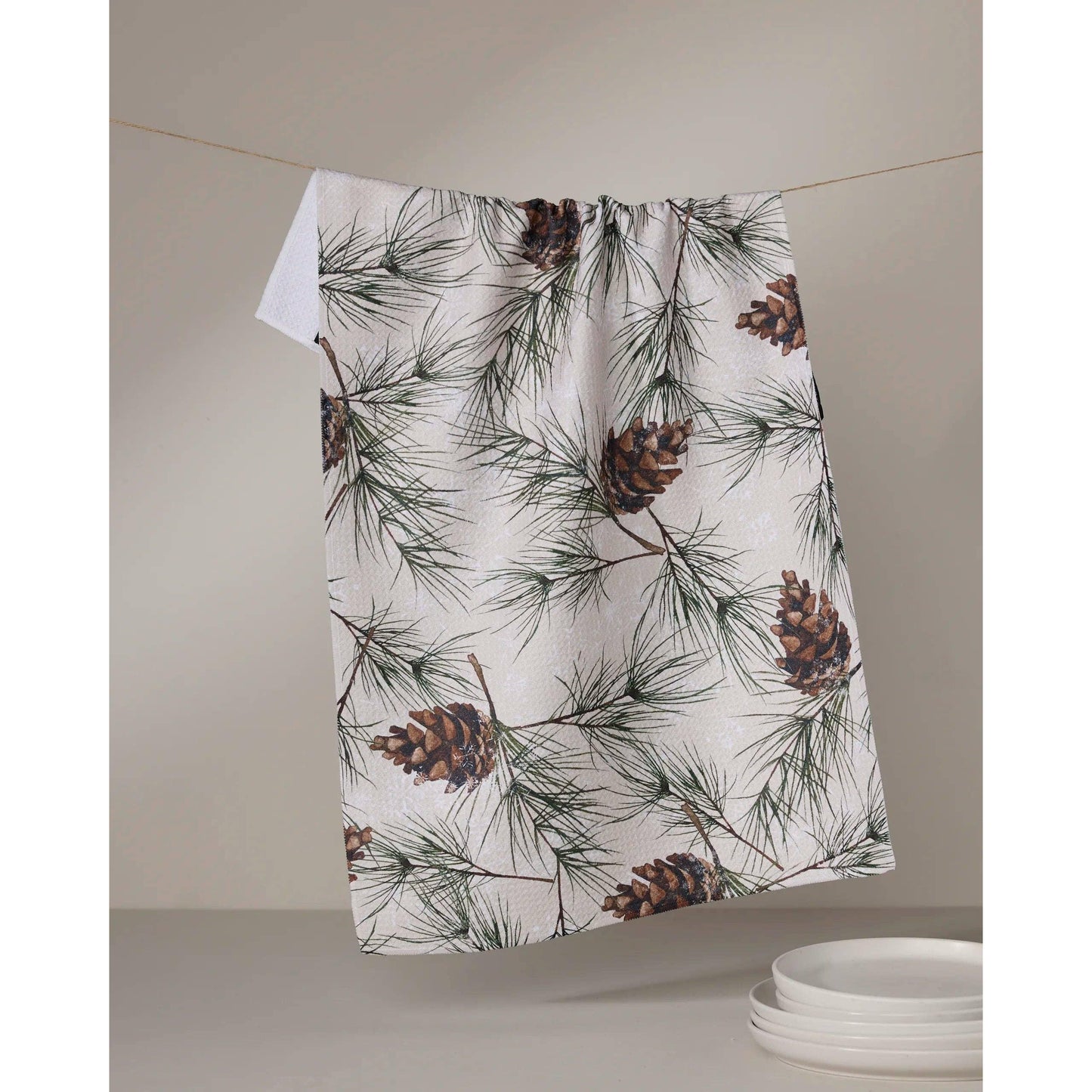 Towel with pine cone and branch pattern hanging on a line