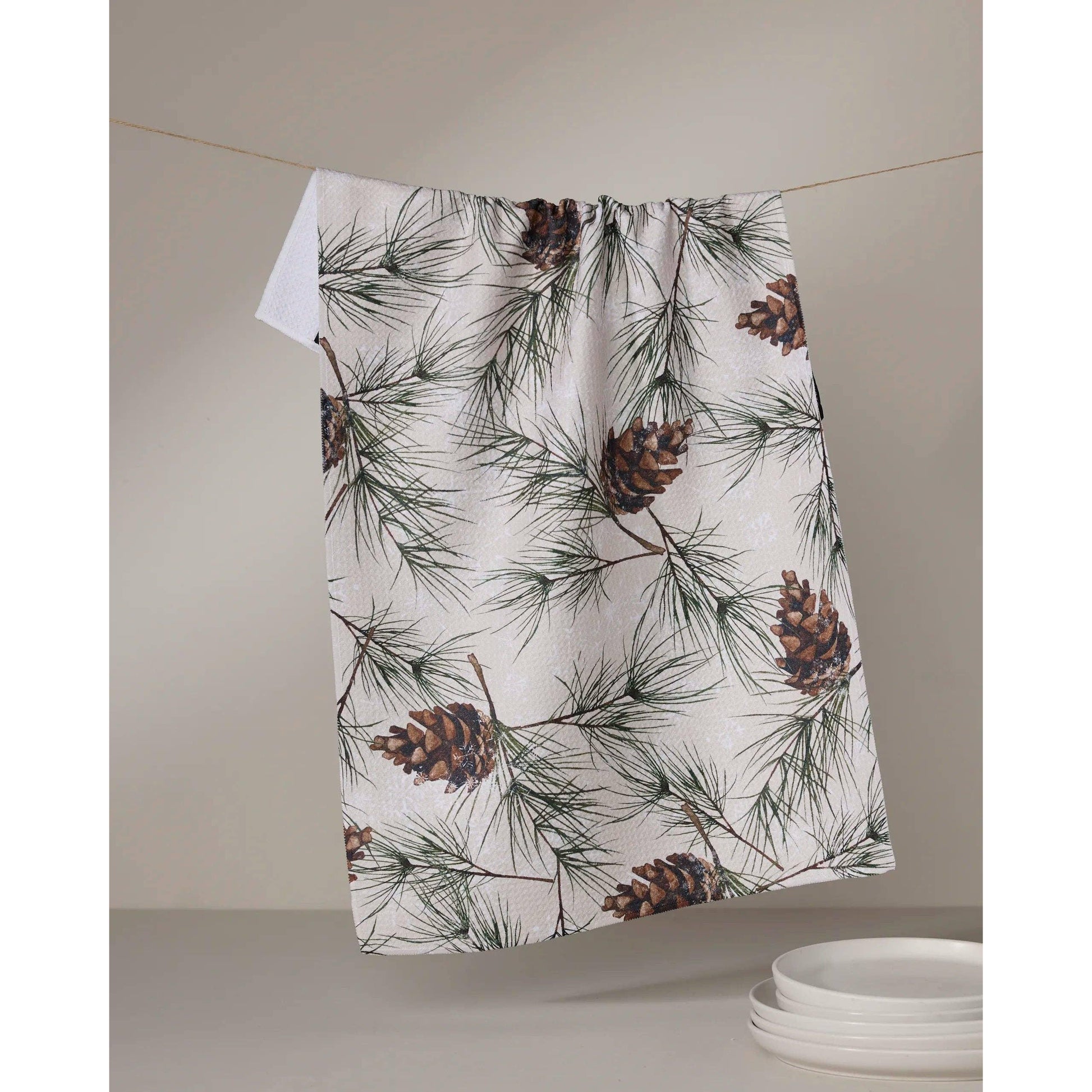 Towel with pine cone and branch pattern hanging on a line
